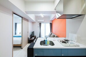Quarto de hotel com cozinha compacta, uma cama, TV e vista para a cidade.