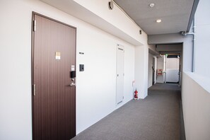 A hallway with doors, a fire extinguisher, and a fire alarm. - SPAZIO 4 Tenjin Minami Annex (Fukuoka City Chuo ku Haruyoshi)