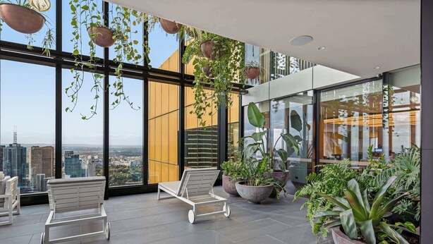 A modern lounge area with large windows, potted plants, and white lounge chairs. - Live in the clouds! 3BD ultra-luxury in Southbank (Southbank)