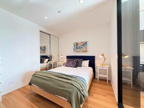 Ein modernes Schlafzimmer mit einem großen Bett, Nachttischen, einem Spiegel und Kunstwerken an der Wand.