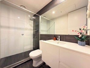 Ein modernes Badezimmer mit einer Duschkabine aus Glas, einer weißen Toilette und einem Waschtisch mit Spiegel.