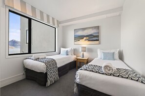 A hotel room with two beds, a window with a view of mountains, a painting on the wall, and a small table with a lamp. - Jaw Dropping Views, Close To The Heart Of Queenstown (Queenstown)
