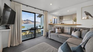 Uma sala de estar moderna com um sofá, uma TV e vista para um lago.