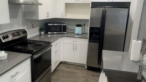 Una cocina moderna con armarios blancos, electrodomésticos de acero inoxidable y piso de madera.
