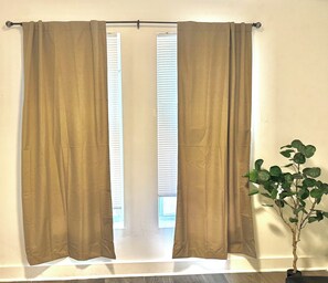 A window with beige curtains and a potted plant beside it.