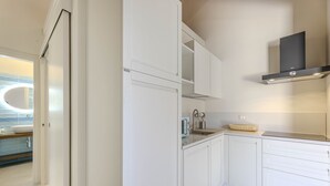 A modern kitchen with white cabinetry, a built-in oven, and a stainless steel range hood. - Villa Acquamarina - Gambero (Capoliveri)