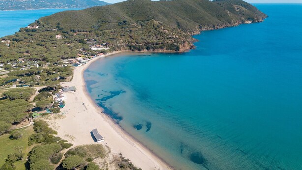 An aerial view of a coastal area with a beach, buildings, and hills. - Villa Acquamarina - Gambero (Capoliveri)