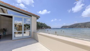 A balcony with a view of a beach and sea, a potted plant, and a person with a camera. - Villa Acquamarina - Gambero (Capoliveri)