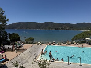Ein Schwimmbecken mit Blick auf das Meer und die dahinterliegenden Hügel.