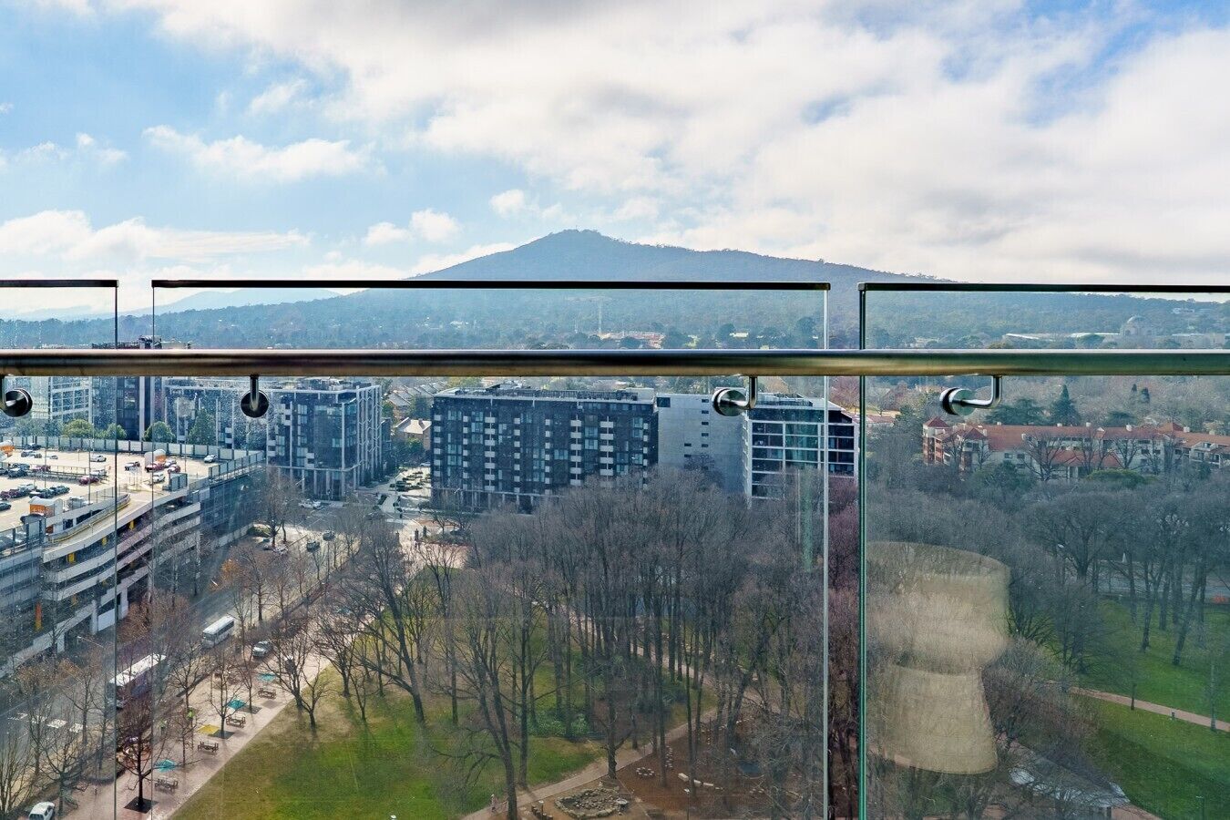 Blick von einem Hochhaus mit einem Berg im Hintergrund, moderne Gebäude und ein Parkplatz.