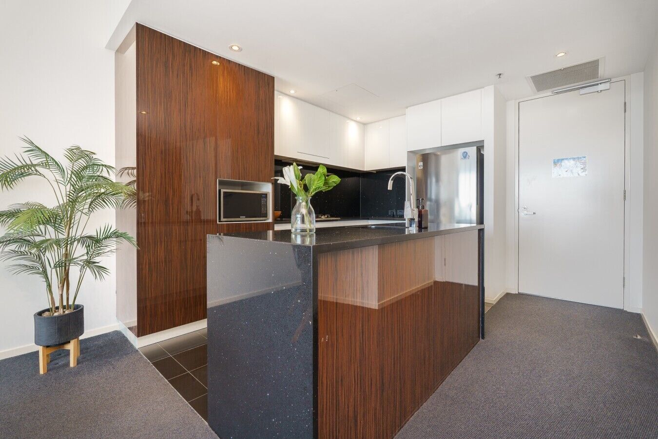 A modern kitchen with a central island, a microwave, and a refrigerator.
