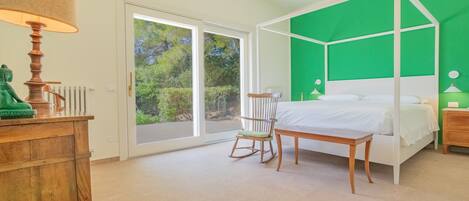 Ein Schlafzimmer mit Himmelbett, Stuhl, Schreibtisch und Lampe.