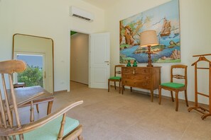 Ein Zimmer mit einem Holzstuhl, einem Holzkasten und einem Bild an der Wand.