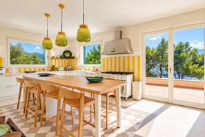 Una cuina moderna amb una illa gran, caires de fusta i vista a l'exterior.