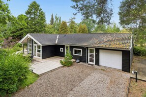 Une maison à deux étages, à l’extérieur sombre, avec un toit recouvert de tuiles et un garage.