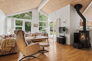 Ein gemütliches Wohnzimmer mit einer Couch, einem Sessel, einem Tisch, einem Fernseher und einem Kaminofen.