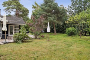 Ein Wohnhaus mit Terrasse, überdachter Außenlounge und Rasenfläche.
