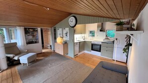 Eine moderne Küche mit weißen Schränken, einem eingebauten Backofen und einem Essbereich mit einer Couch und einem Teppich.