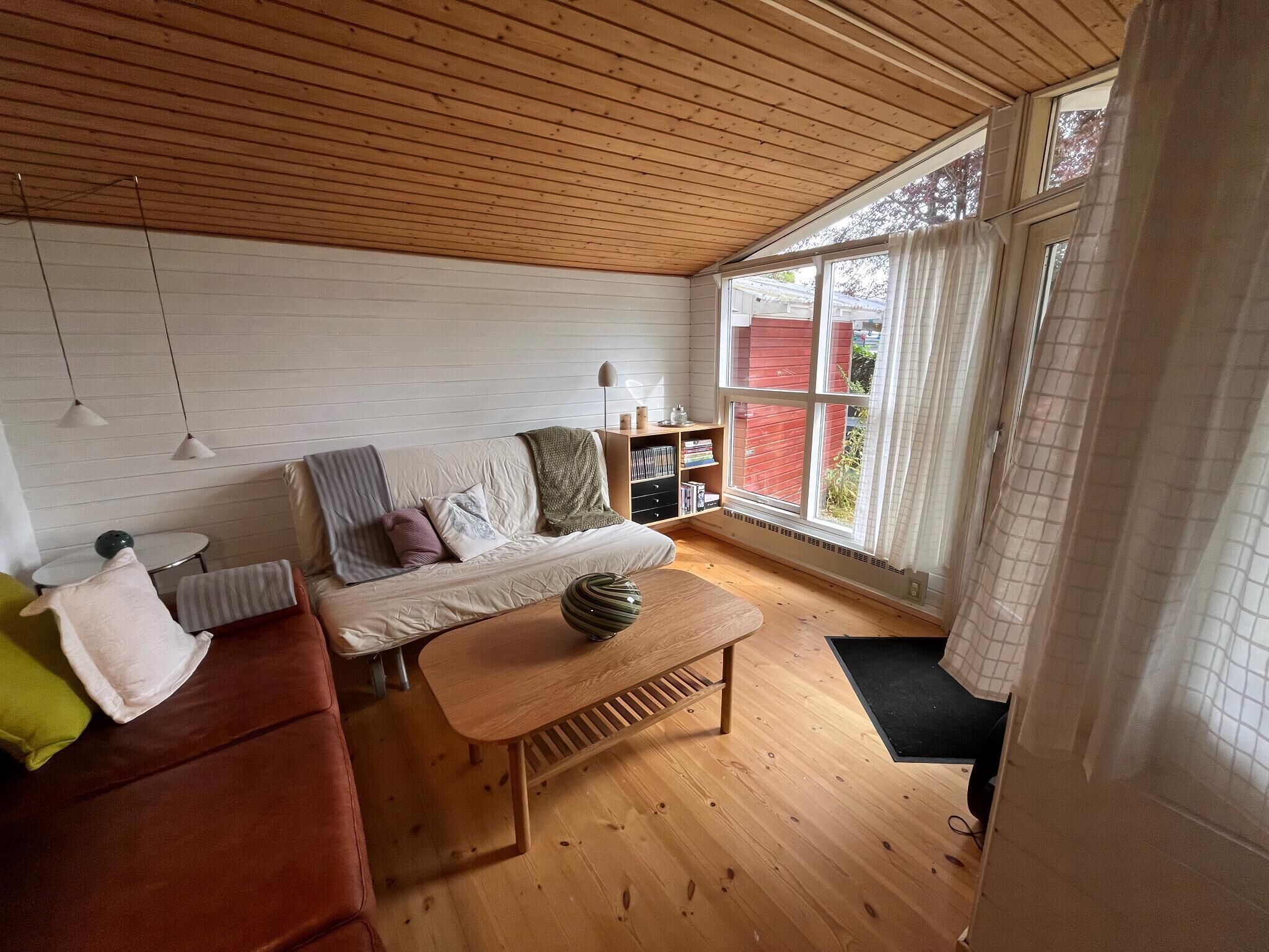 Un salon chaleureux avec un plafond en bois, un canapé, une table basse et une bibliothèque.