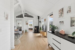 Ein großzügiger Raum mit hoher Decke, Kamin, Fernseher und einer Essecke mit Tisch und Stühlen.