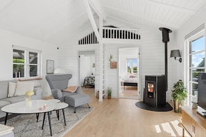 Un amplio salón con techo alto, chimenea, sofá, mesa de centro y televisor.