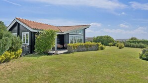 Ett modernt hus med ett sluttande tak, en inglasad veranda och en välskött gräsmatta.