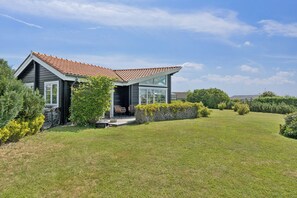 Ein modernes Haus mit Satteldach, einer überdachten Veranda und einem gepflegten Rasen.
