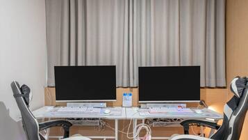 A room with two desks, each with a computer monitor, keyboard, and mouse. There are two chairs, one on each desk.