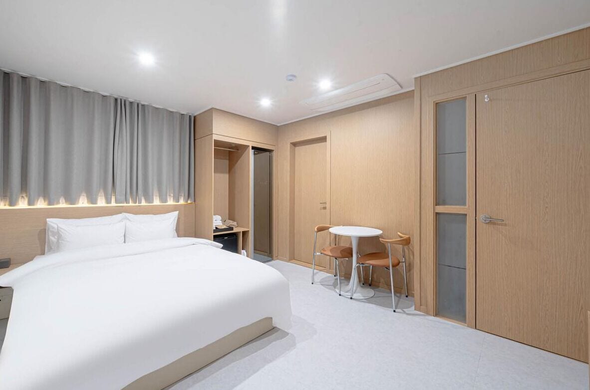 A hotel room with a bed, a desk, a chair, and a wardrobe.