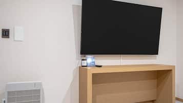 A room with a large flat-screen TV mounted on the wall, a wooden console table, a white radiator, and a control panel with a remote.