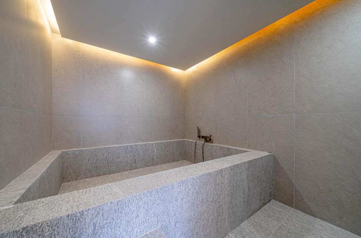 A modern bathroom with a freestanding bathtub, tiled walls, and a ceiling light.