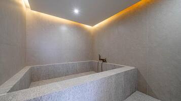 A modern bathroom with a freestanding bathtub, tiled walls, and a ceiling light.