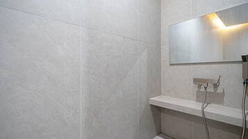 A modern bathroom with a large mirror, a shower area, and a built-in bench.