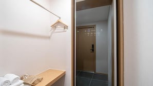 Ein Hotelzimmer mit einer hölzernen Bank, einem Handtuchhalter und einer Tür mit digitaler Anzeige.