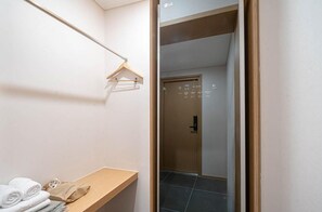 A hotel room with a wooden bench, a towel rack, and a door with a digital display. - Brown Dot Tongyeong Jukrim (Tongyeong)