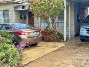Une allée menant à une résidence, avec une voiture garée, une porte de garage et le numéro 63 sur la maison.