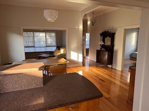 A spacious room with a wooden floor, a dining area with a table and chairs, a sofa, and a window providing natural light. - Newport House 2 bedroom, 1 sofa bed, 1 bathroom (Newport)
