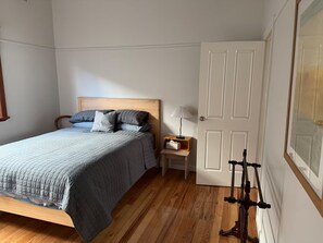 Une chambre à coucher avec un lit, une table de chevet, une lampe et une porte.