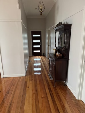 A hallway with wooden flooring, a dark wooden cabinet, and a door with illuminated panels. - Newport House 2 bedroom, 1 sofa bed, 1 bathroom (Newport)