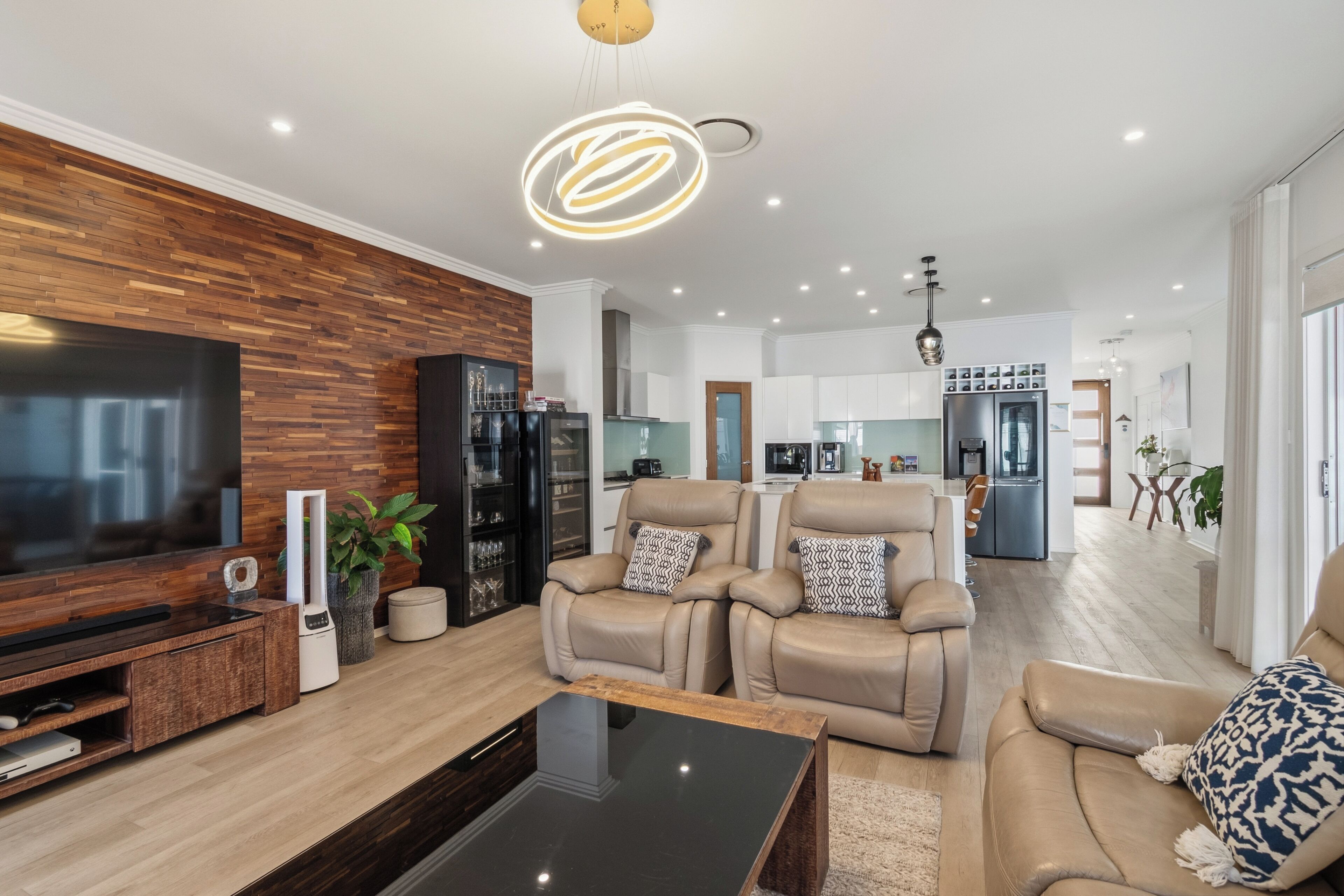 Ein modernes Wohnzimmer mit Flachbildfernseher, Ledersofas und einer Holzvertäfelung.