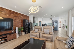 Ein modernes Wohnzimmer mit Flachbildfernseher, Ledersofas und einer Holzvertäfelung.