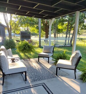 An outdoor patio with two cushioned chairs, a small table, and a potted plant. - 3-bedroom Charming Farmhouse Near Boyne Mountain (Boyne City)