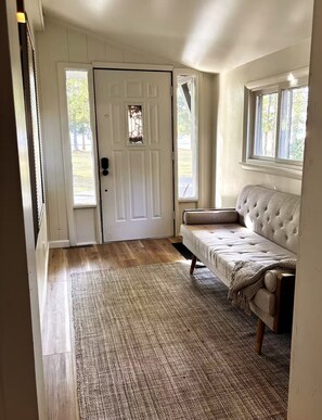 Et værelse med en hvid dør, en beige sofa og en tæppe med et mønster.
