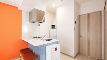 Cocina compacta con microondas integrado, un lavamanos y un refrigerador pequeño.