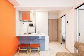A compact kitchen with a microwave, gas stove, and a sink. There are two stools and a chair. - SPAZIO 4 Tenjin Minami (Fukuoka City Chuo ku Haruyoshi)