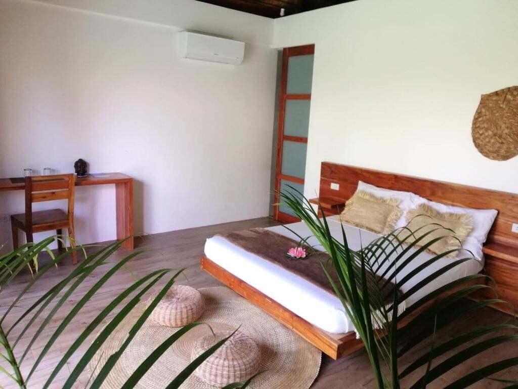 Un dormitorio con una cama de madera, una mesita de noche, una silla y un ventanal grande.