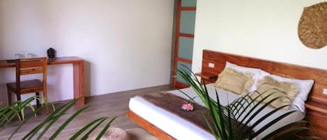 A bedroom with a wooden bed, a bedside table, a chair, and a large window.