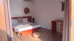 Un dormitorio con una cama, una mesita de noche, una silla, un tapete tejido y un adorno en la pared.