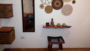 Una habitación con un espejo, cestas tejidas fijadas a la pared y una pequeña estatua de Buda sobre una repisa.