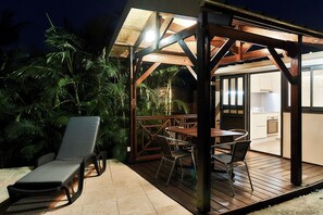 Eine Terrasse im Freien mit Holzdeck, einer Liege und einem Tisch mit Stühlen.